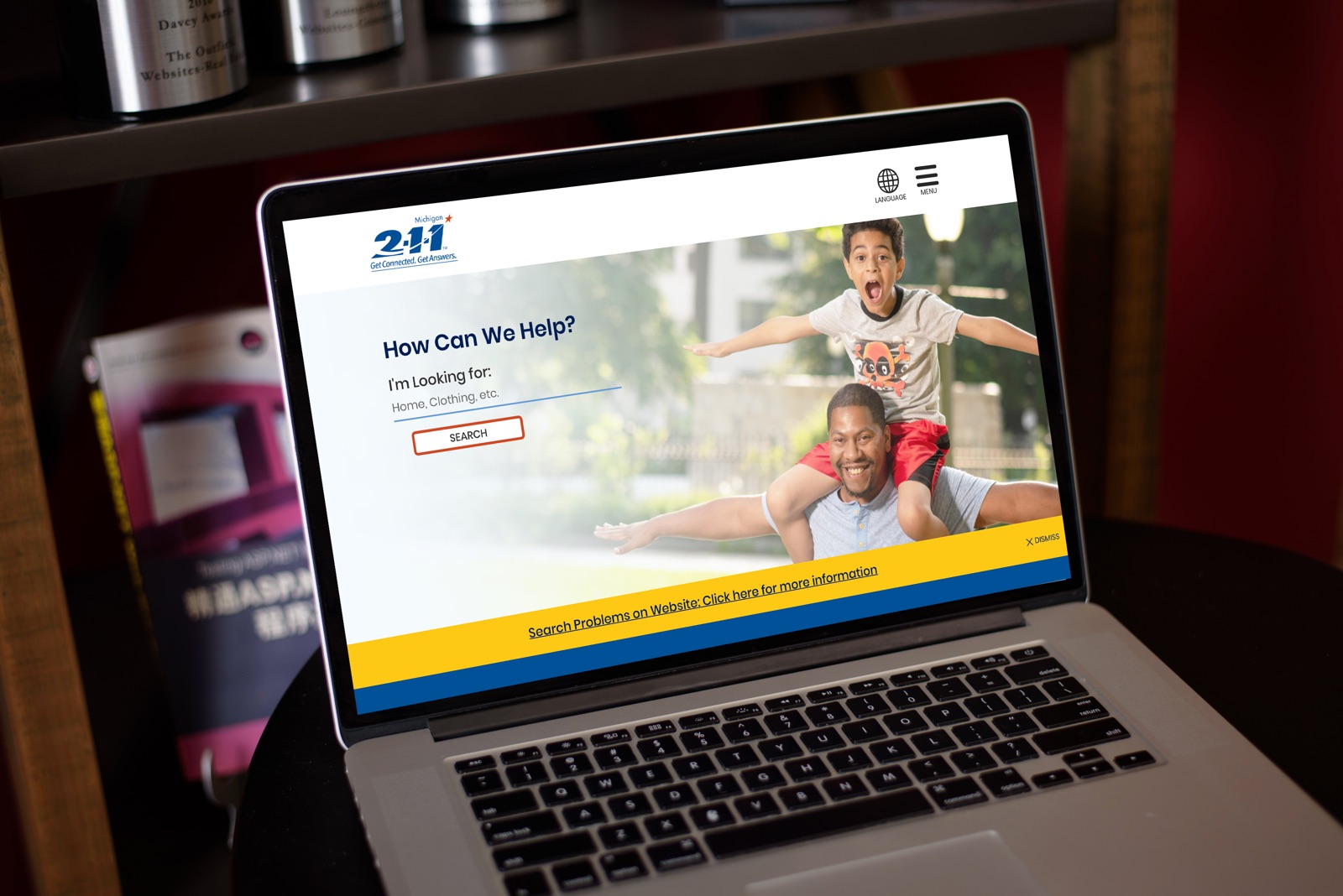 The Michigan 2-1-1 website homepage on a laptop